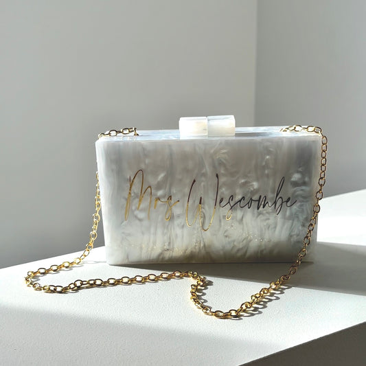 white acrylic marble look clutch with metallic gold writing of customers choice. gold chain attached whoch is detachable 